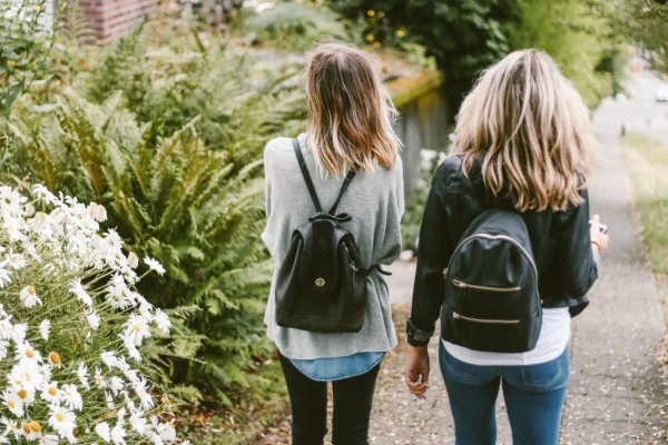 Two girls walking together from behind